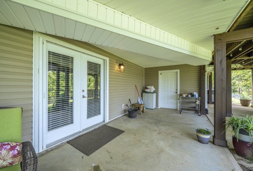 Covered concrete patio with white French doors featuring integrated blinds