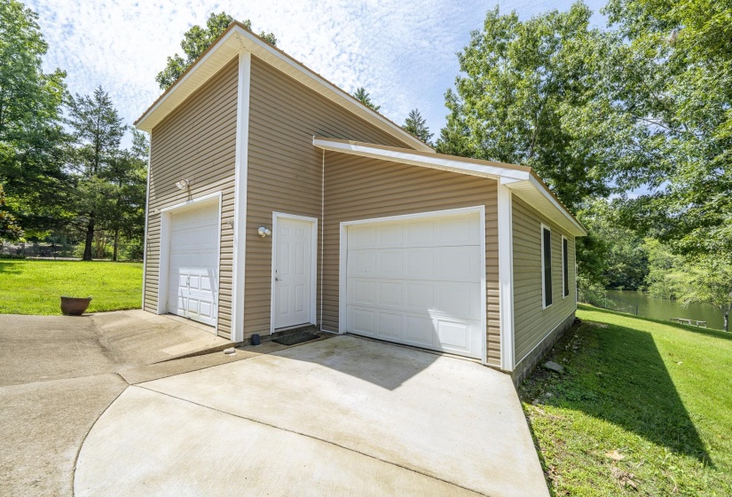 Two-car garage with vinyl siding and white garage doors, featuring an additional entry door