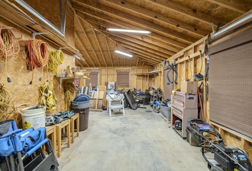 Spacious utility building featuring exposed wood frame construction, concrete flooring, and an open vaulted ceiling