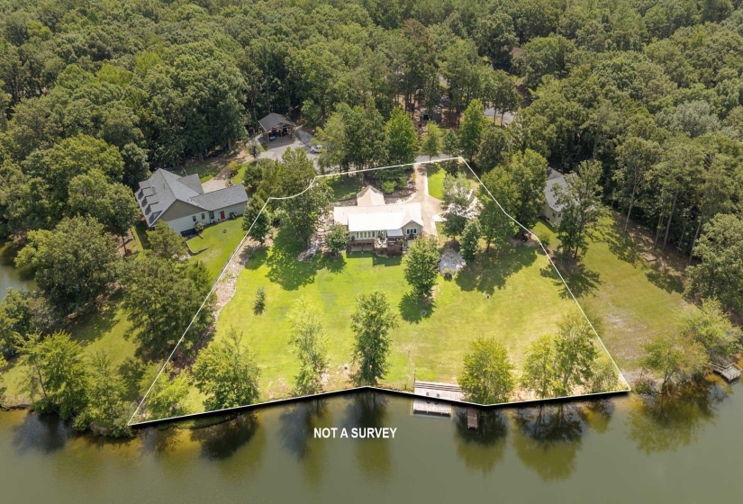 Expansive waterfront property featuring a main residence, mature trees, and a private dock