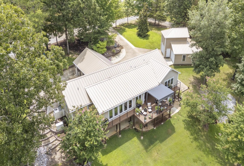 Residential property featuring a light-colored metal roof, multi-level decking, and a separate outbuilding with a matching roof