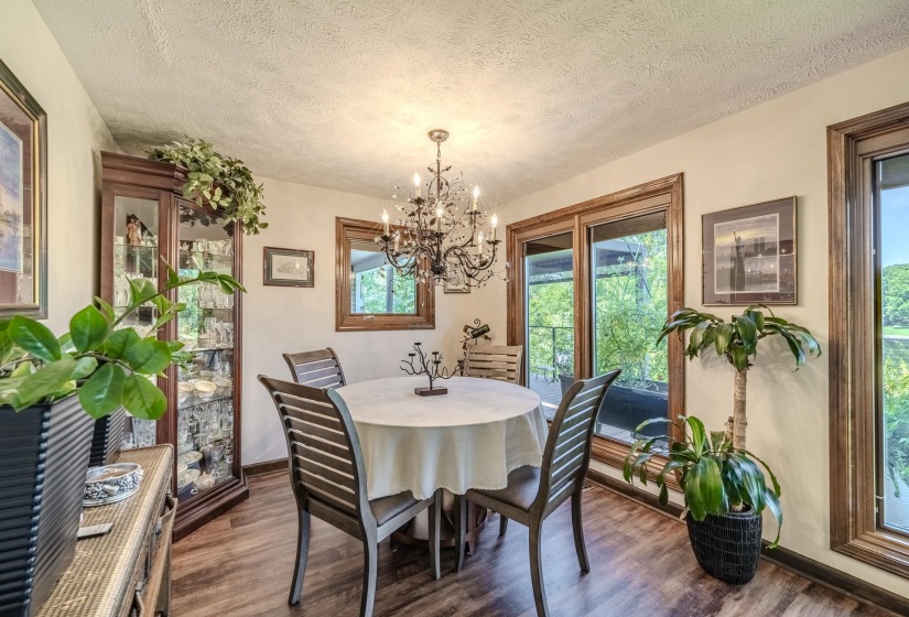 Dining area featuring wood-finish flooring, a decorative chandelier, and extensive natural light from multiple glass panel doors and windows with wood trim