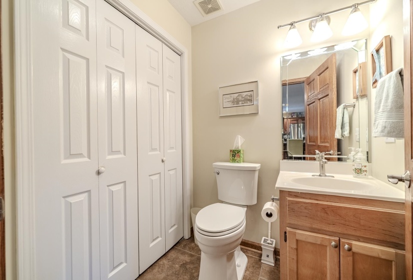 Bathroom featuring a light wood-finish vanity with a white basin sink, polished chrome faucet, and a large wall mirror