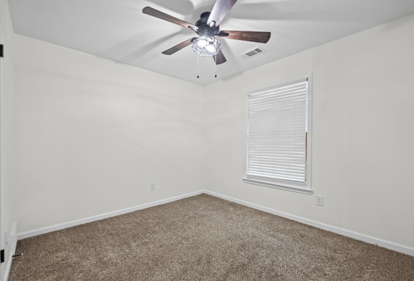 Carpeted room featuring a ceiling fan with light fixture, white walls, and a window with blinds