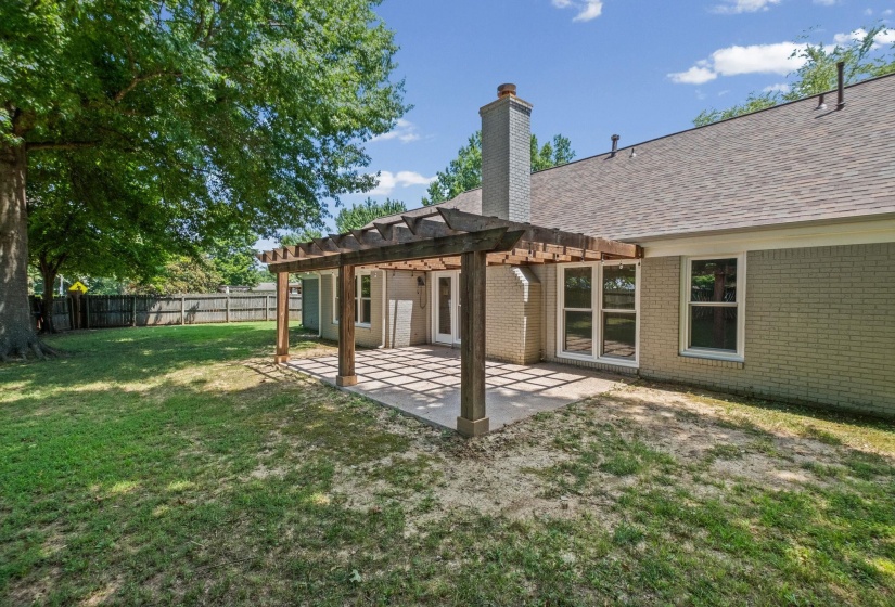 Rear exterior featuring a large pergola-covered patio with concrete flooring