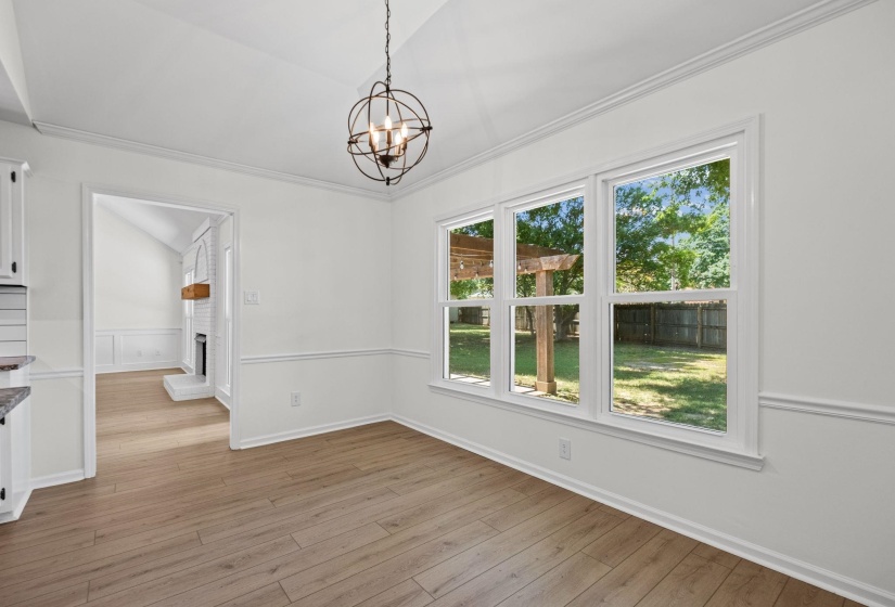 Spacious interior featuring wood-finish flooring, white walls, and bright natural light from three large windows