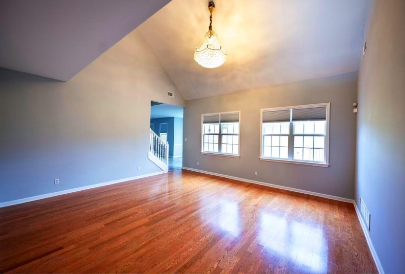 Spacious interior featuring high vaulted ceilings, polished wood-finish flooring, and a crystal chandelier