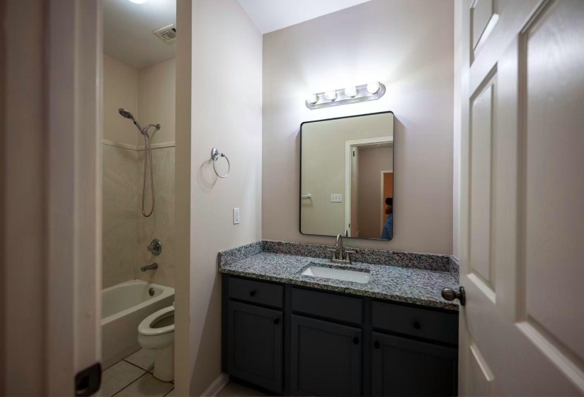 Bathroom featuring a dark vanity with a light-colored countertop, an undermount sink, and an overhead vanity light