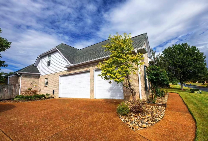 Brick and siding exterior featuring a multi-car garage with white doors, a gabled roofline, and dormer windows
