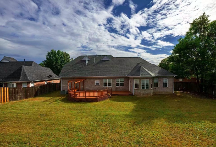 Expansive backyard featuring a brick exterior, multi-level wood deck, privacy fencing, and mature trees