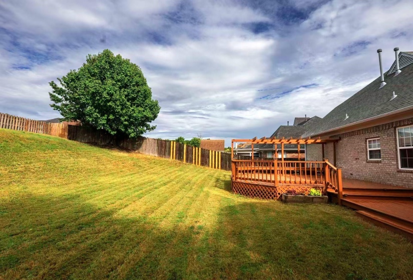 Expansive backyard featuring a multi-tiered wood deck, a wood pergola, and a privacy fence