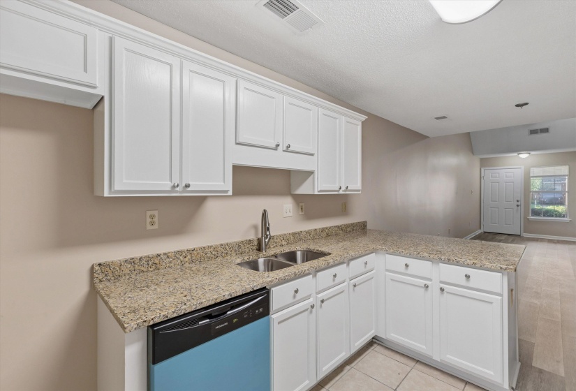 Kitchen featuring white cabinetry, granite-finish countertops, and a dual-basin stainless steel sink with a gooseneck faucet