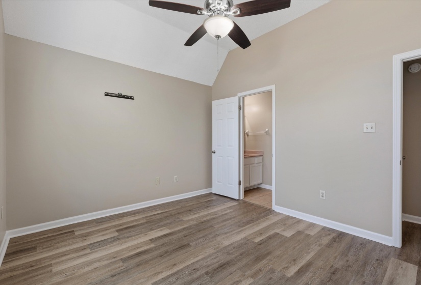 Vaulted ceiling room featuring wood-finish flooring, a ceiling fan, and access to a bathroom with a vanity and sink