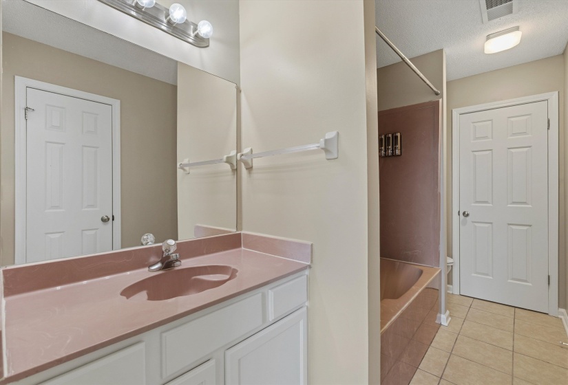 Bathroom featuring a single vanity with a solid surface countertop, integrated sink, and white cabinetry