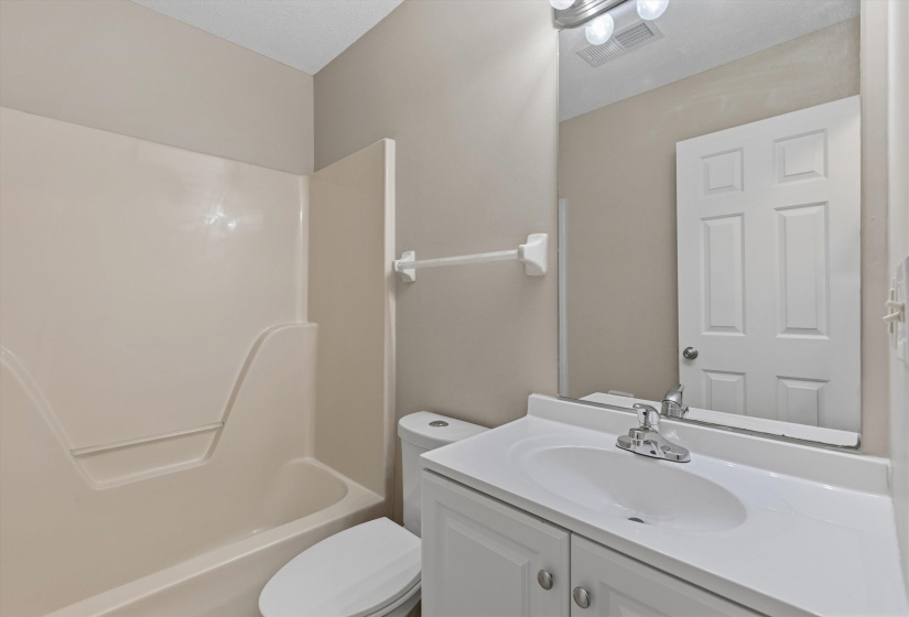 Bathroom featuring a white vanity with an integrated sink, chrome faucet, and a large wall-mounted mirror