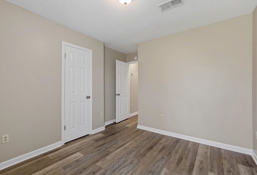 Neutral-toned interior with wood-finish flooring, white baseboards, and a six-panel interior door