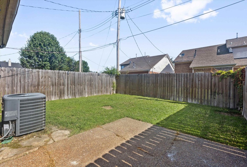 Fenced backyard featuring a grassy lawn and concrete patio