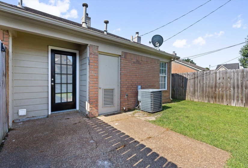 Exterior featuring a full-light paneled door, brick facade, horizontal siding, concrete patio, and a grass lawn