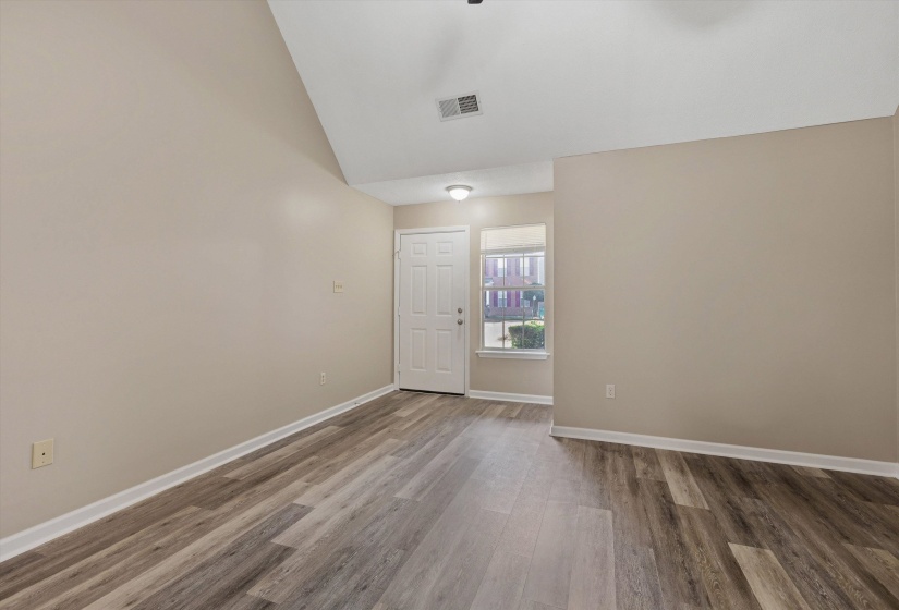 Entryway featuring wood-finish flooring, a white paneled door, and a multi-pane window