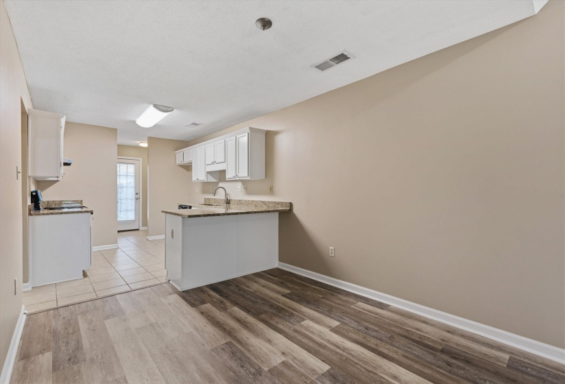 Kitchen featuring white cabinetry, granite-style countertops, an undermount sink, and tiled flooring