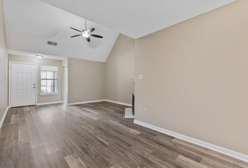Spacious interior featuring wood-finish flooring, vaulted ceilings, a ceiling fan, and a built-in fireplace