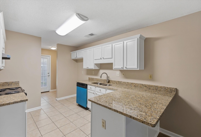 Kitchen featuring white cabinetry, granite-look countertops, tile flooring, and a stainless steel sink with a gooseneck faucet