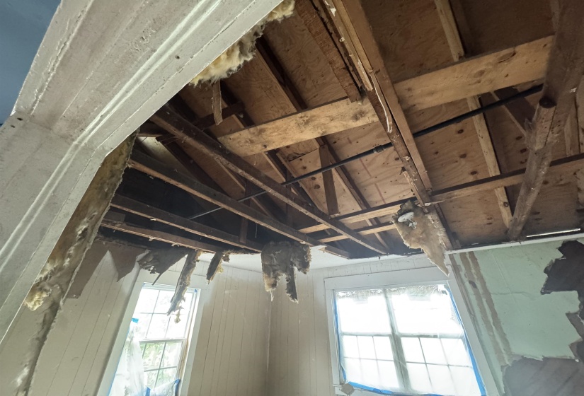 Exposed ceiling joists and subflooring with visible piping provide an opportunity for renovation