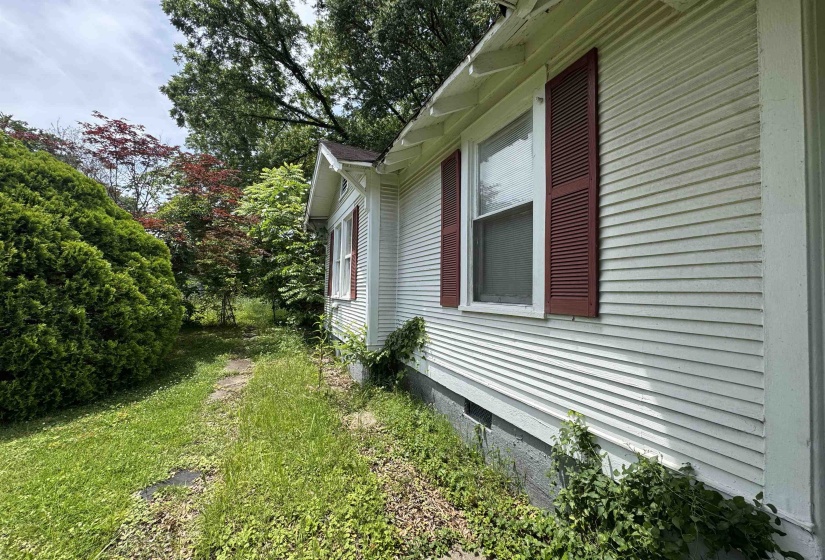 White horizontal siding exterior with red louvered shutters and a brown shingle roof