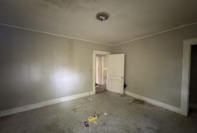 Interior room featuring a ceiling-mounted light fixture, crown molding, and a paneled door