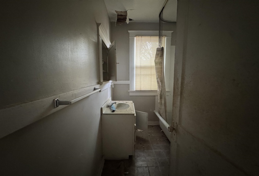 Bathroom featuring a vanity with an integrated sink, medicine cabinet, window with blinds, and bathtub with a shower curtain rod