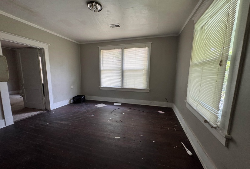 Interior room featuring dark wood-finish flooring, two windows with blinds, light gray walls, white trim, and an overhead light fixture