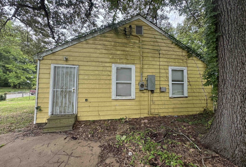 Yellow-sided exterior with dual windows and a security screen door