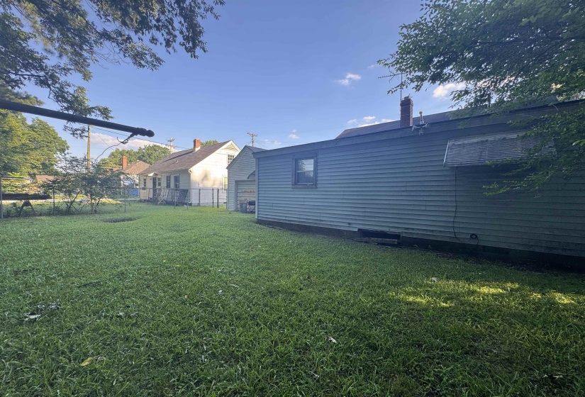 Expansive grassy yard area alongside the property, featuring mature trees providing natural shade