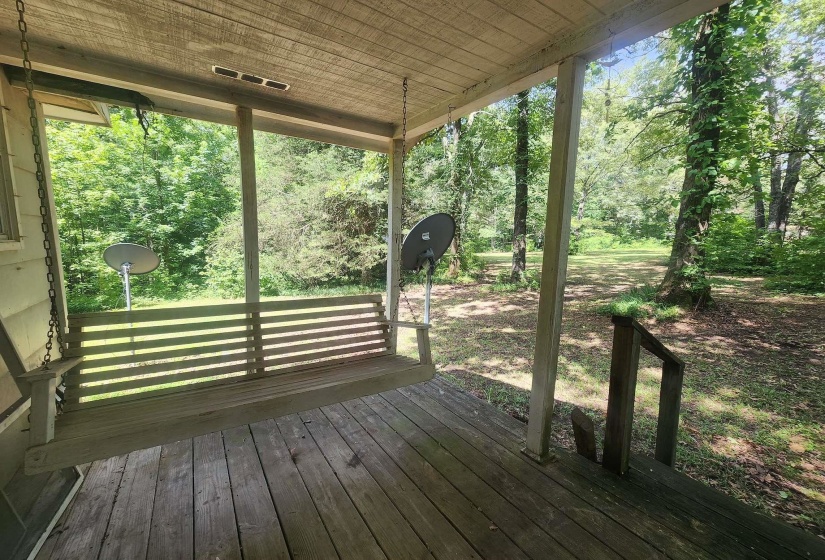 Covered porch with wood plank flooring and a porch swing