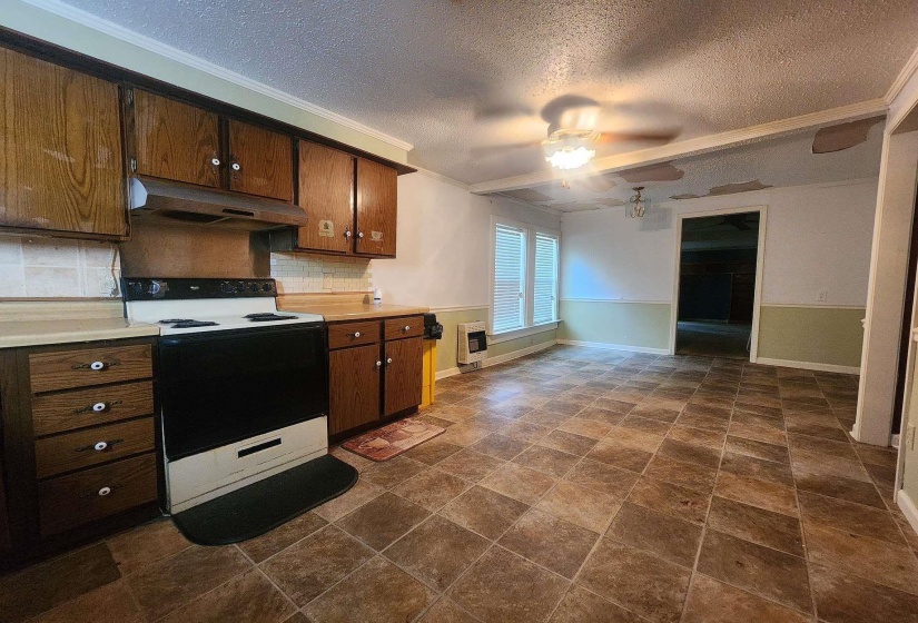 Kitchen featuring wood-finish cabinetry, a freestanding range, and a tiled backsplash
