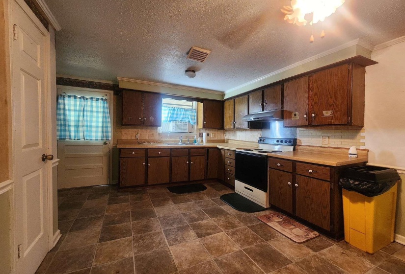 Kitchen featuring wood-finish cabinetry, laminate countertops, and a tile backsplash