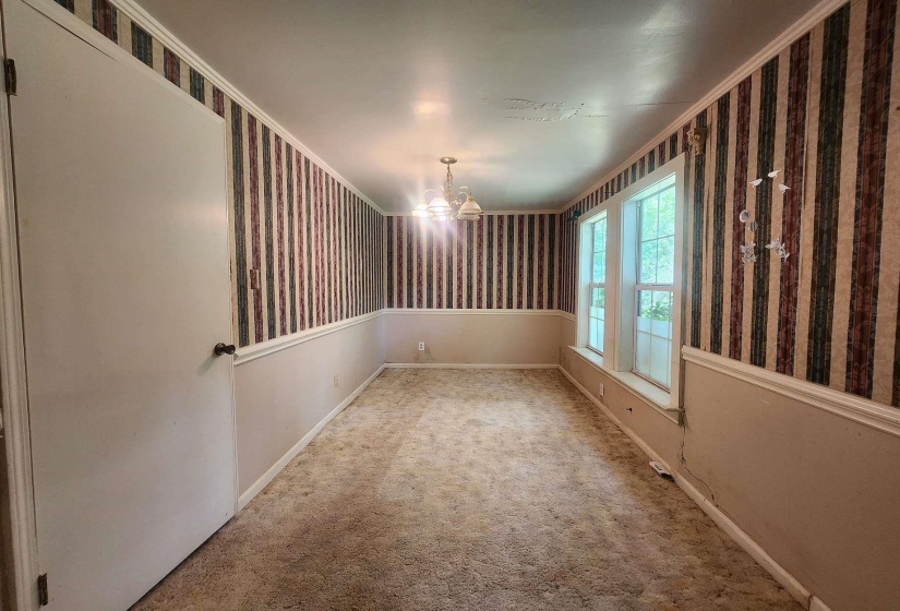 Room featuring striped wallpaper, white crown molding, and wainscoting