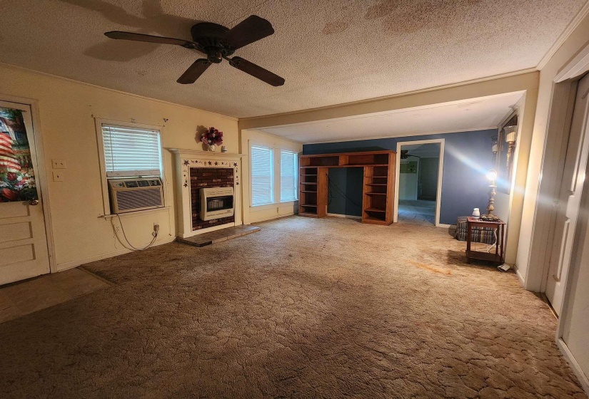 Spacious living area featuring a ceiling fan, multiple windows with blinds, and a built-in media center with shelving