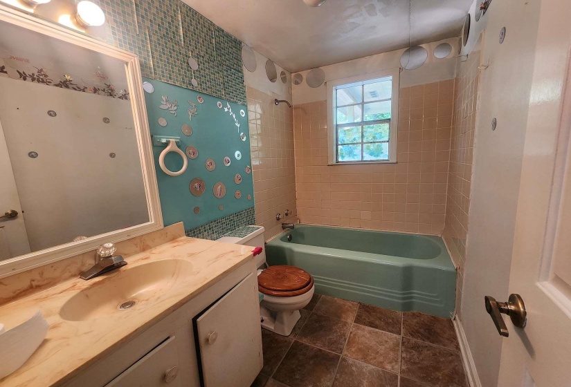 Bathroom featuring a light blue bathtub, tiled flooring, and a window for natural light