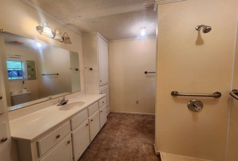 Bathroom featuring a double vanity with integrated sinks, white cabinetry, and a large wall-mounted mirror