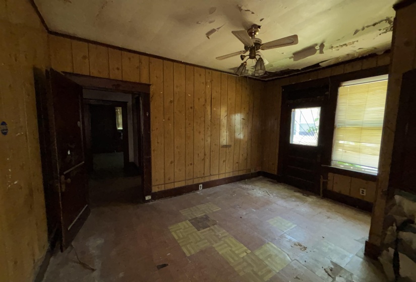 Room with vertical wood paneling and a ceiling fan light fixture
