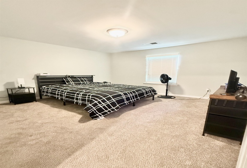 Spacious room featuring neutral carpet flooring, a single window with blinds, and white wall finishes