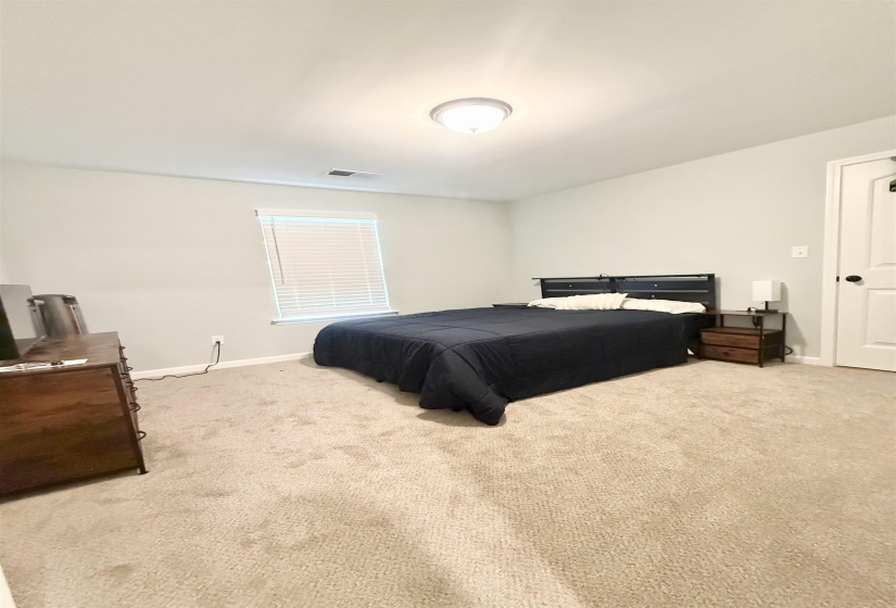 Carpeted bedroom with neutral wall tones and a single window featuring horizontal blinds