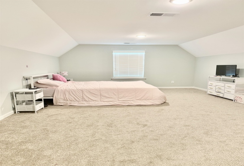 Spacious room featuring vaulted ceilings, recessed lighting, neutral wall tones, window with blinds, and soft carpet flooring
