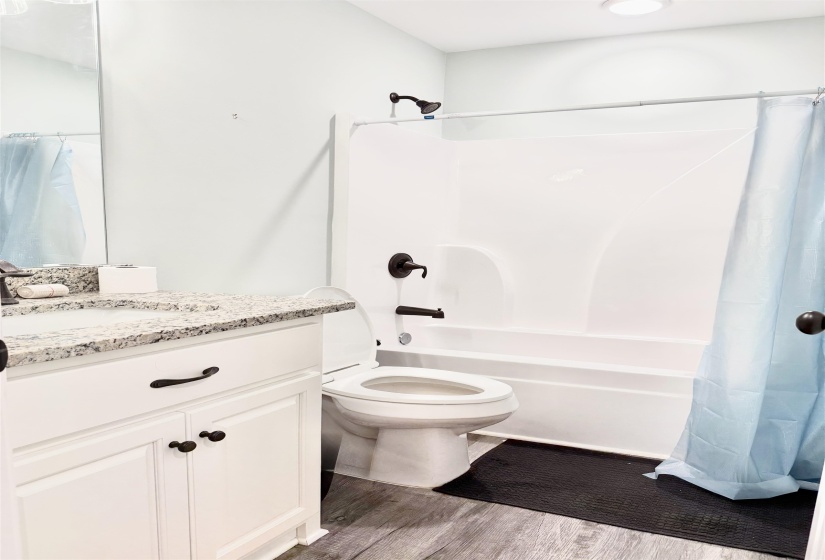 Bathroom featuring a white vanity with a granite-style countertop, undermount sink, and black hardware