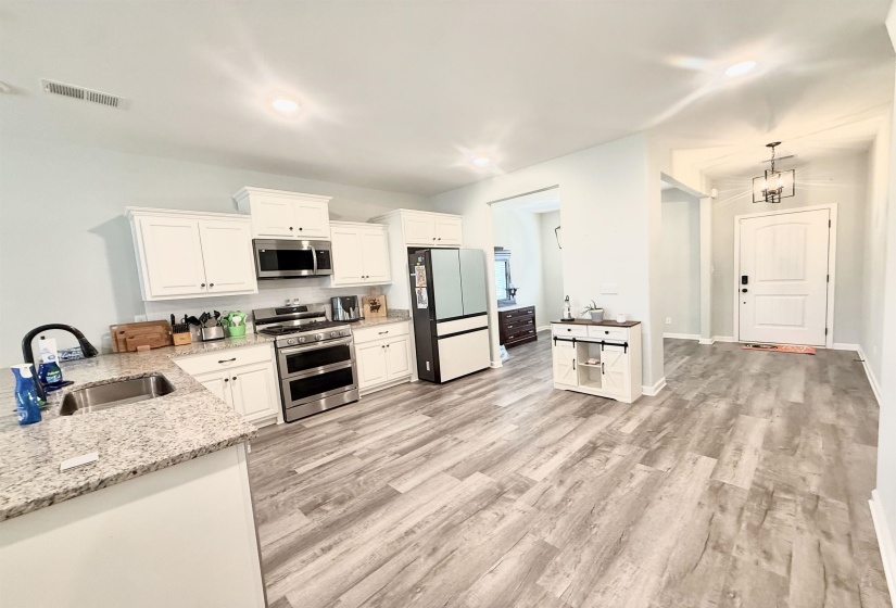Spacious kitchen featuring white cabinetry, light-toned wood-finish flooring, and granite countertops
