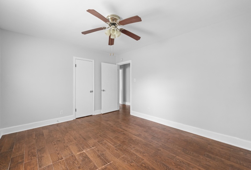 Spacious room featuring wood-finish flooring, light gray walls, and white trim