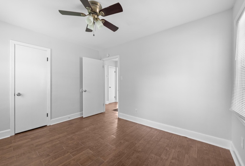 Spacious room featuring wood-finish flooring, light gray wall paint, and white trim