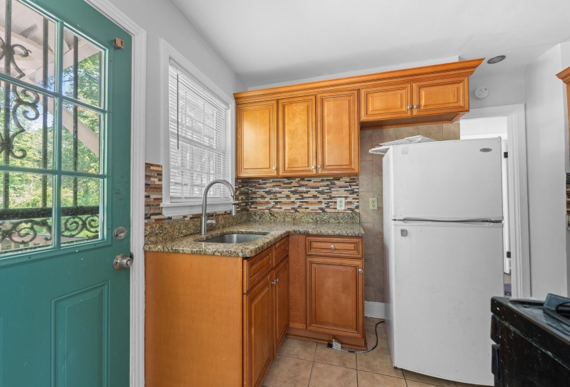 Kitchen featuring wood cabinetry, granite-style countertops, mosaic tile backsplash, and a stainless steel sink with a gooseneck faucet