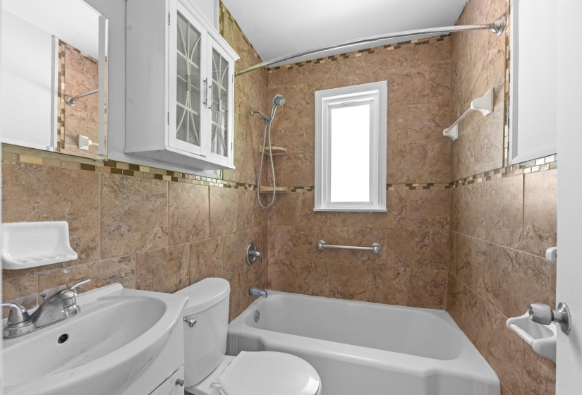 Bathroom featuring full-height brown tiling with a decorative mosaic accent band